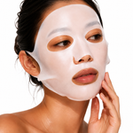 A close-up of a woman wearing a white sheet mask on her face, with her hand touching her cheek, against a plain white background.